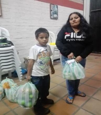 Madre y niño recibiendo sus bolsas de alimentos